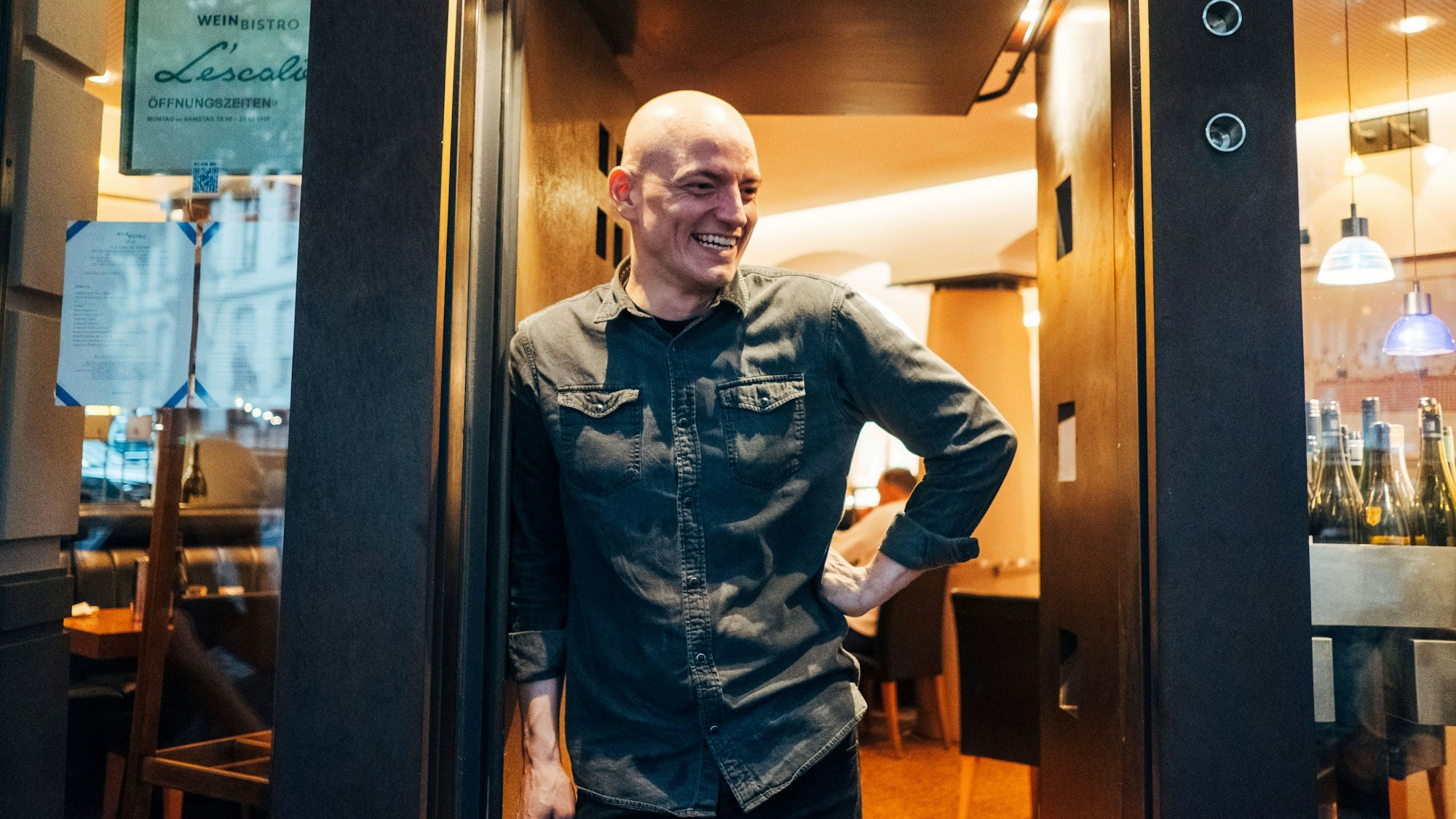 Ein Mann steht lächelnd in einem Türrahmen.