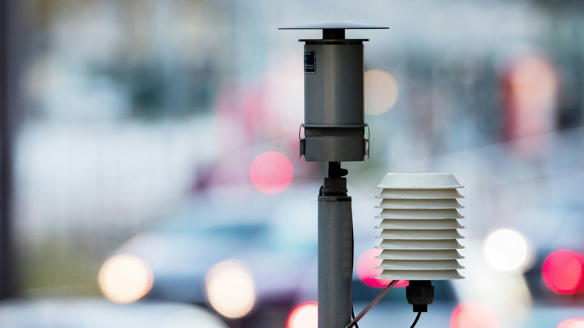 Das Bild zeigt die Messstation, im Hintergrund sieht man verschwommen Autos.