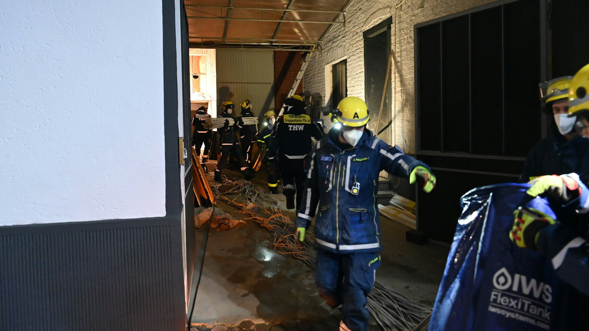 Zu sehen sind Helfer des Technischen Hilfswerks in einem Haus. Sie tragen Atemschutzmasken.