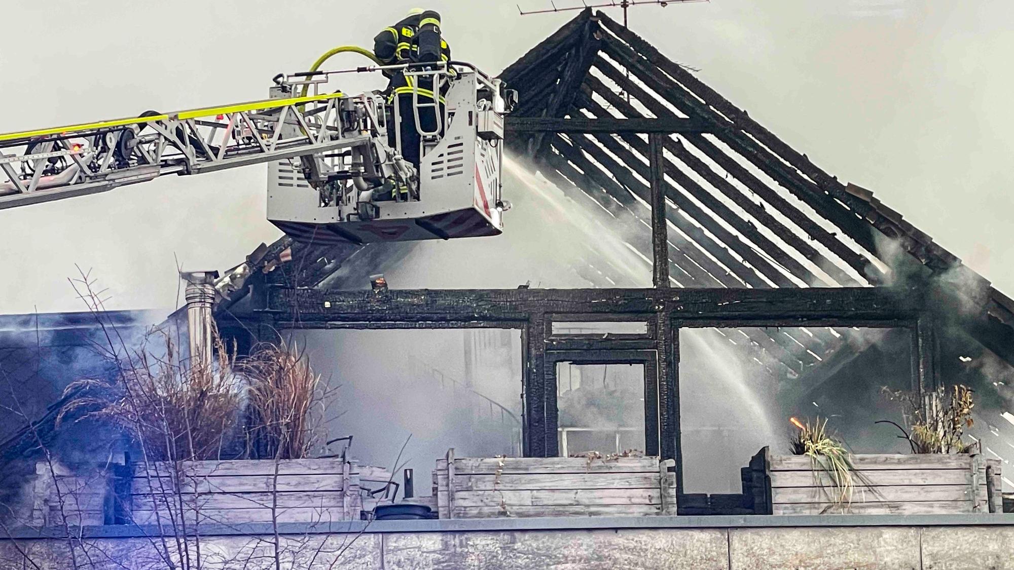 Das Bild zeigt den bereits ausgebrannten Dachstuhl. Die Feuerwehr löscht von der Drehleiter aus.