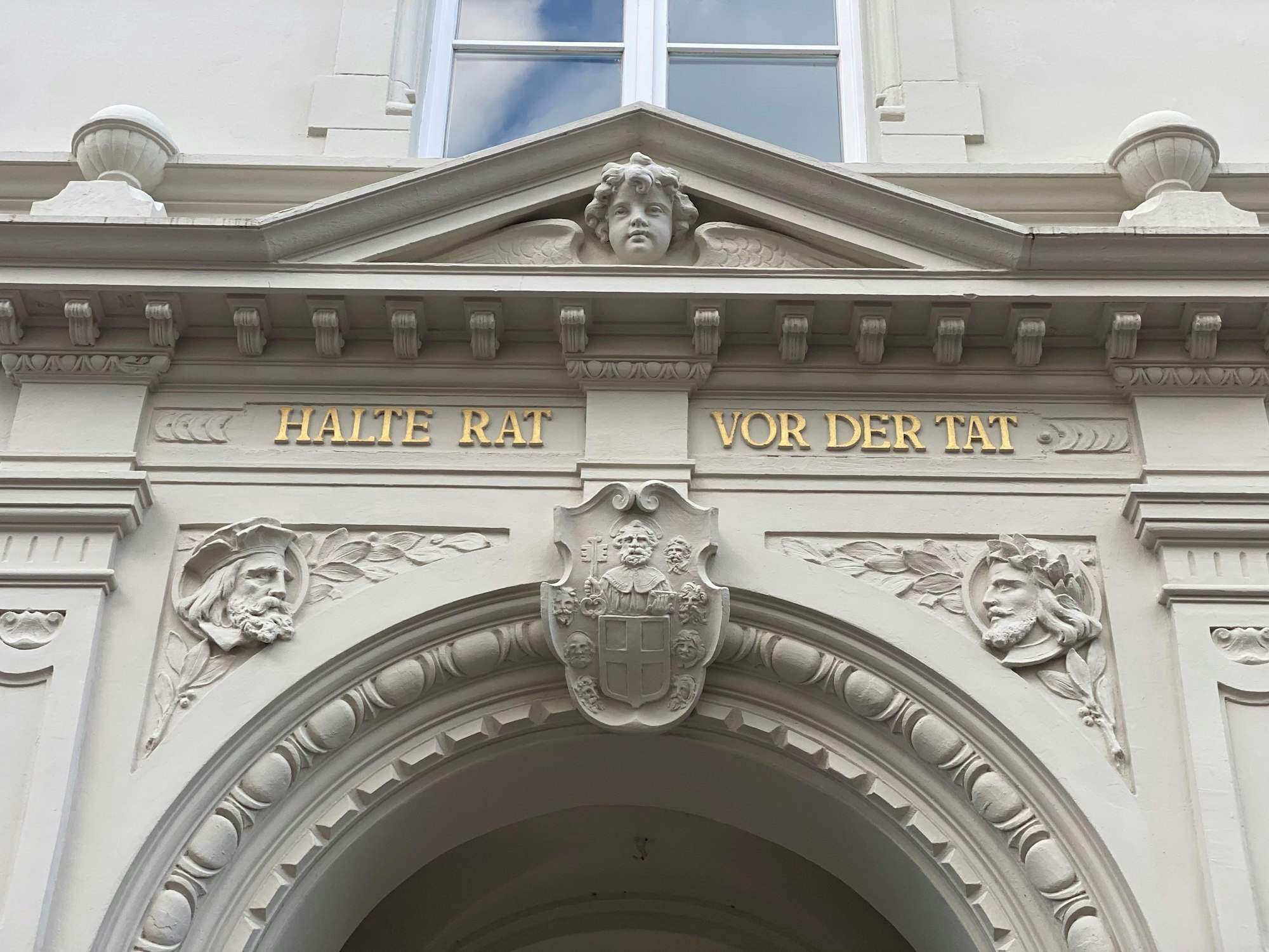 Zu sehen ist eine Inschrift am Brühler Rathaus. Sie lautet „Halte Rat vor der Tat“.