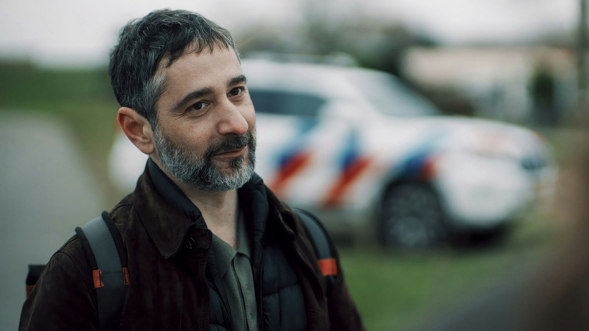 Denis Moschitto steht vor einem bunt gestreiften Auto.