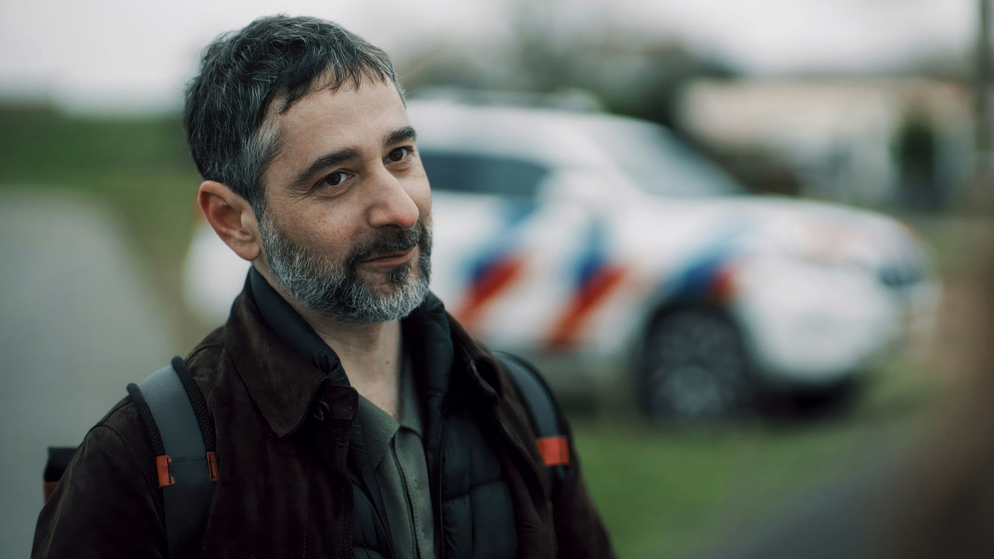 Denis Moschitto steht vor einem bunt gestreiften Auto.