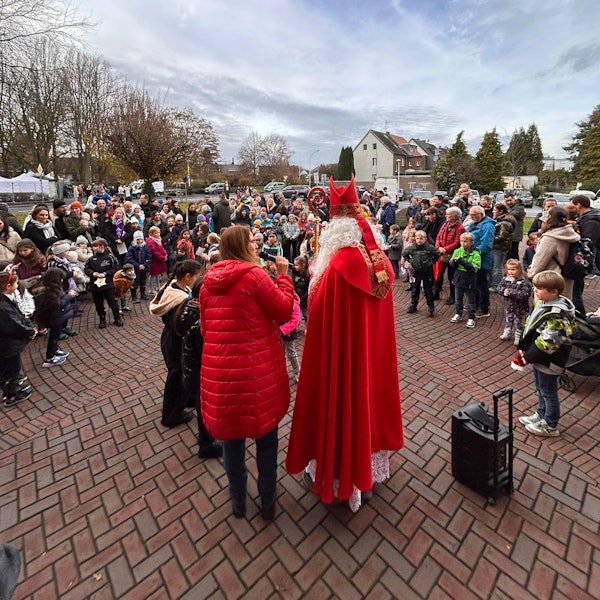 Auf dem Bild ist ein Nikolaus vor einer Menschengruppe zu sehen.