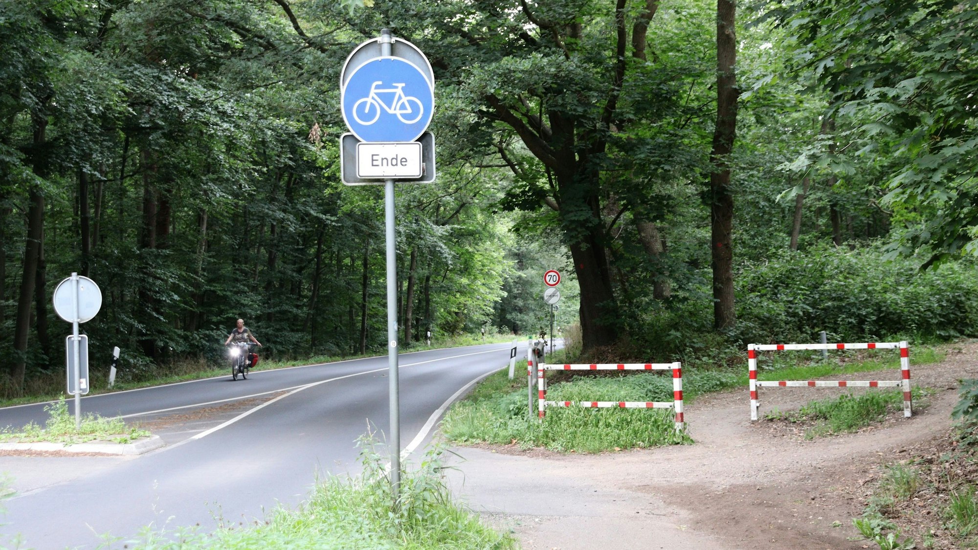 An einer Straße liegt ein Radweg, der an einer Schranke endet.