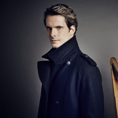 Xavier de Maistre posiert neben einer Harfe.