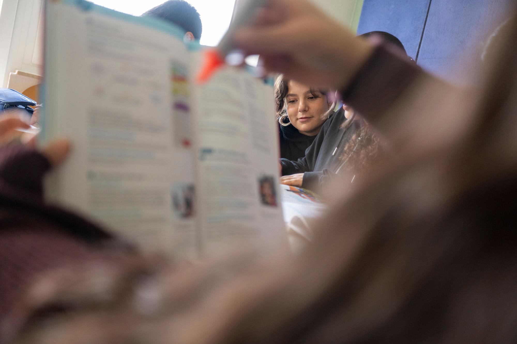 Ein Mädchen hält ein Schulheft hoch und markiert mit einem orangefarbenen Edding eine Stelle. Es ist eine Szene aus der kostenlosen Hausaufgabenbetreuung beim Verein Kölner Appell gegen Rassismus.