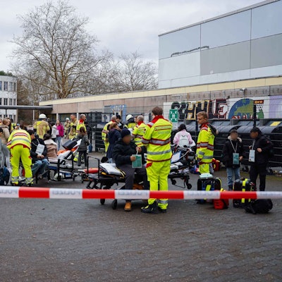 Kräfte von Feuerwehr und Rettungsdienst kümmern sich auf einem Schulhof um Schülerinnen und Schüler.