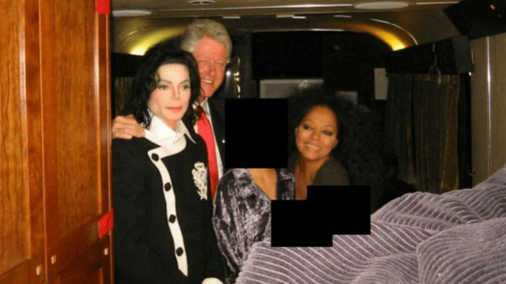 Bill Clinton legt seine Hand auf die Schulter von Michael Jackson (l.). Diana Ross sitzt daneben.