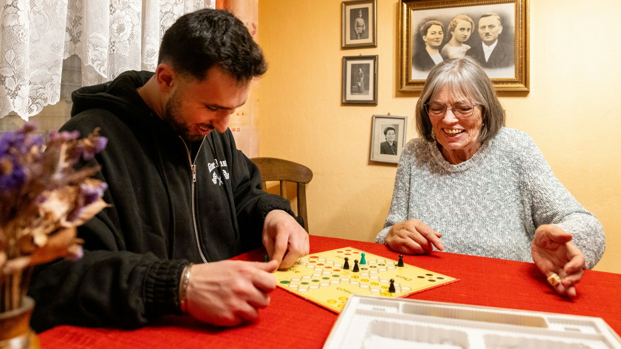 Medal Raslan und Heidrun Brandt spielen zusammen „Mensch ärgere dich nicht“ und lachen dabei.