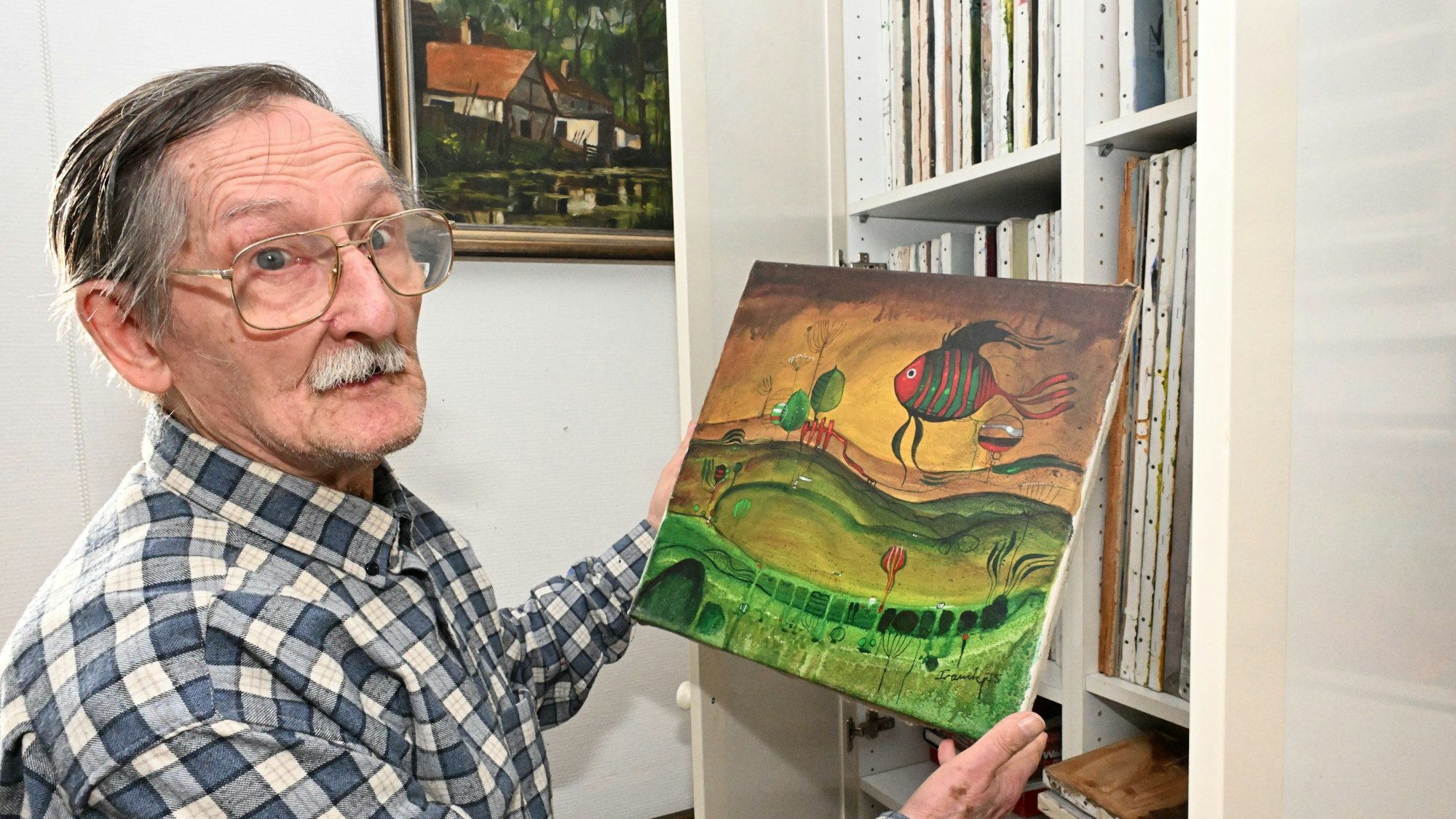 Dieter Framke präsentiert ein Werk, auf dem ein Fisch zu sehen ist.