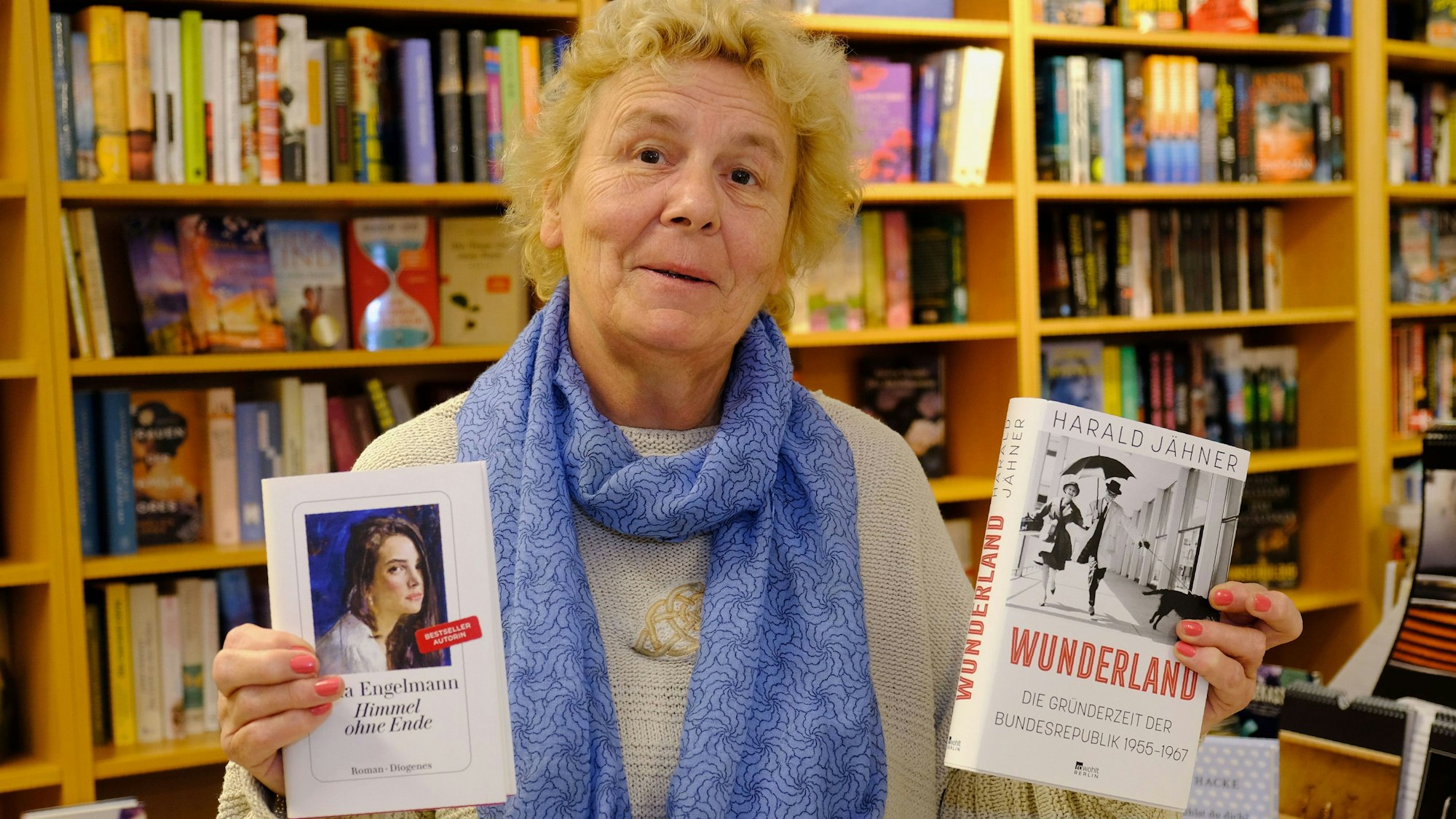 Das Bild zeigt die Buchhändlerin, die zwei Bücher in der Hand hält.