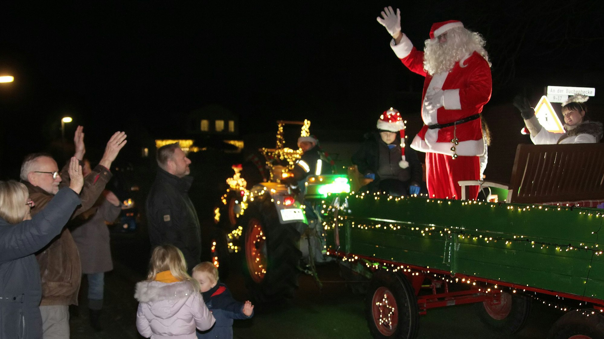 Der Weihnachtsmann winkt Kindern und Erwachsenen zu.