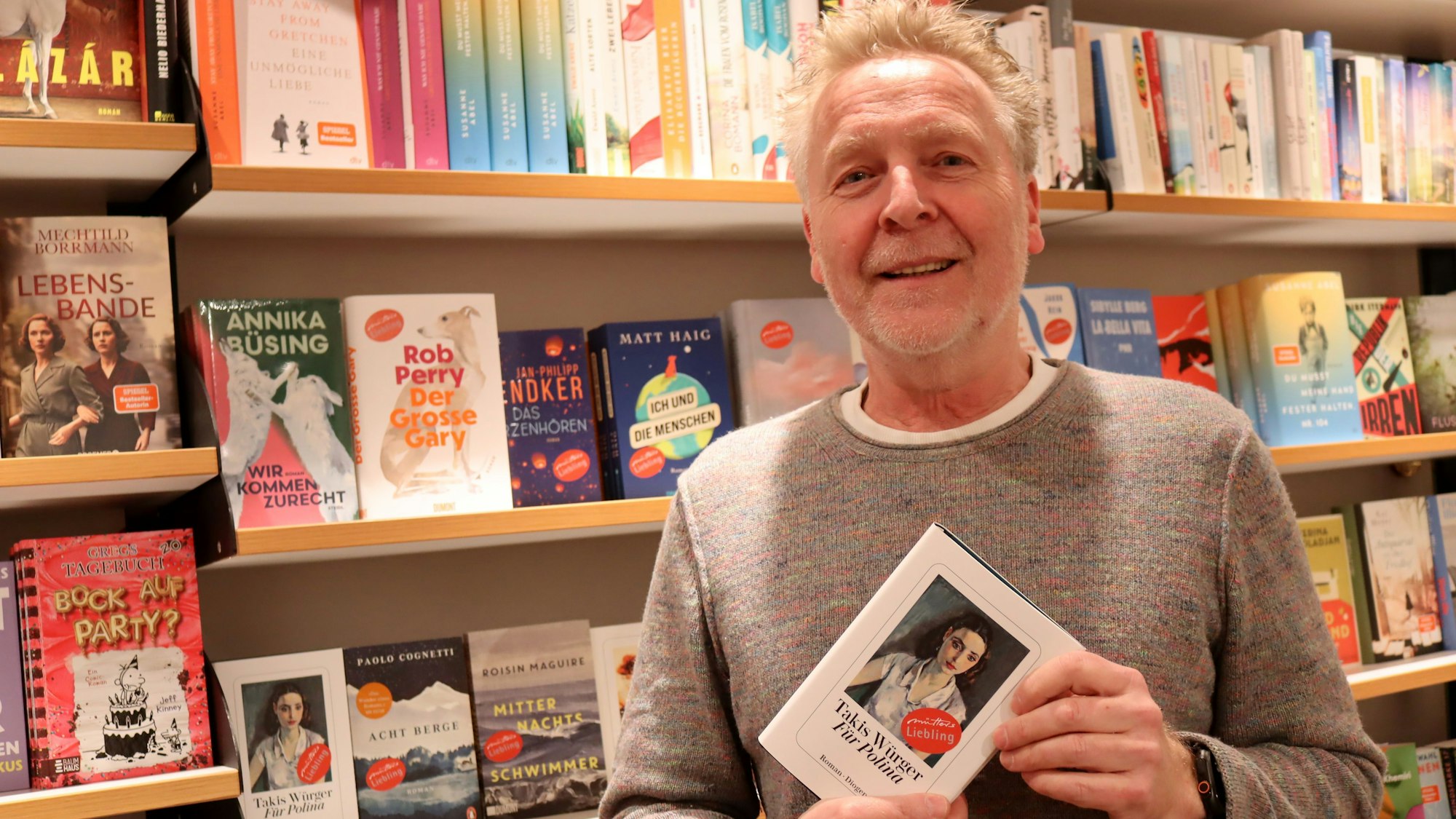 Das Bild zeigt die Buchhändler mit einem Buch in der Hand.