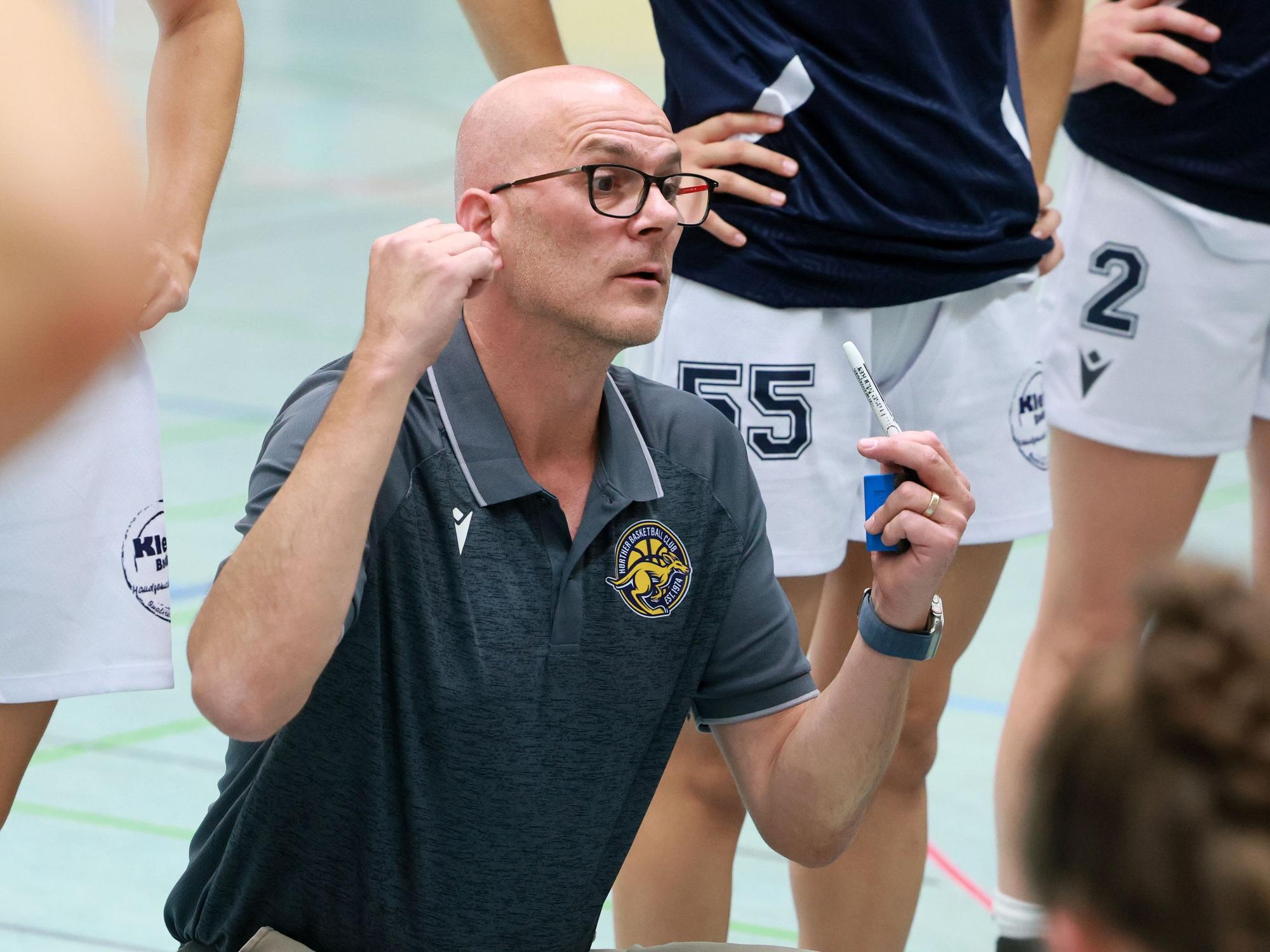 Das Foto zeigt den Hürther Basketballtrainer, der seine Spielerinnen mit erhobenen Händen anspricht.