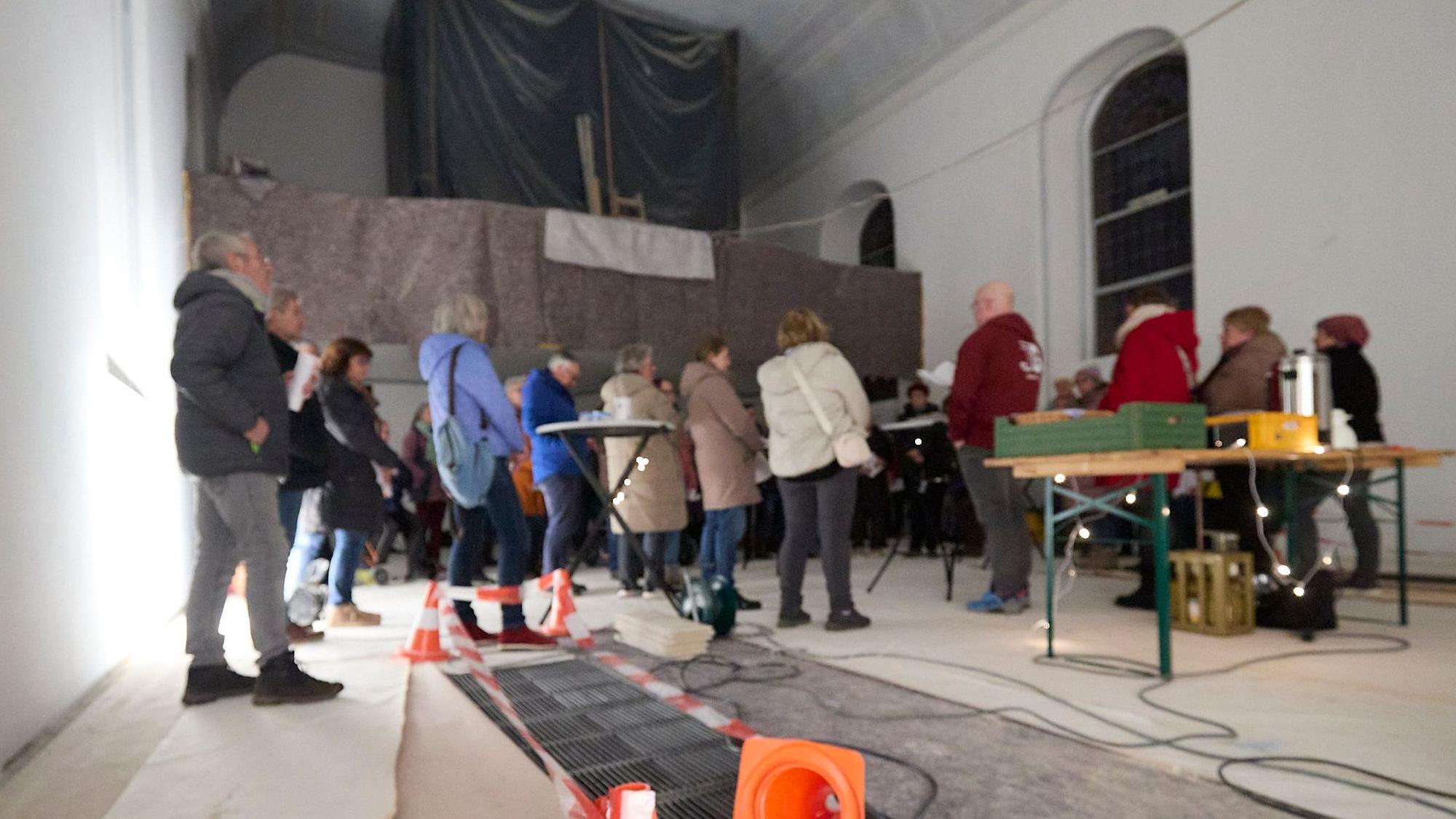 Menschen stehen in der Kirche und singen. Im Hintergrund ist die eingehauste Orgel zu sehen.
