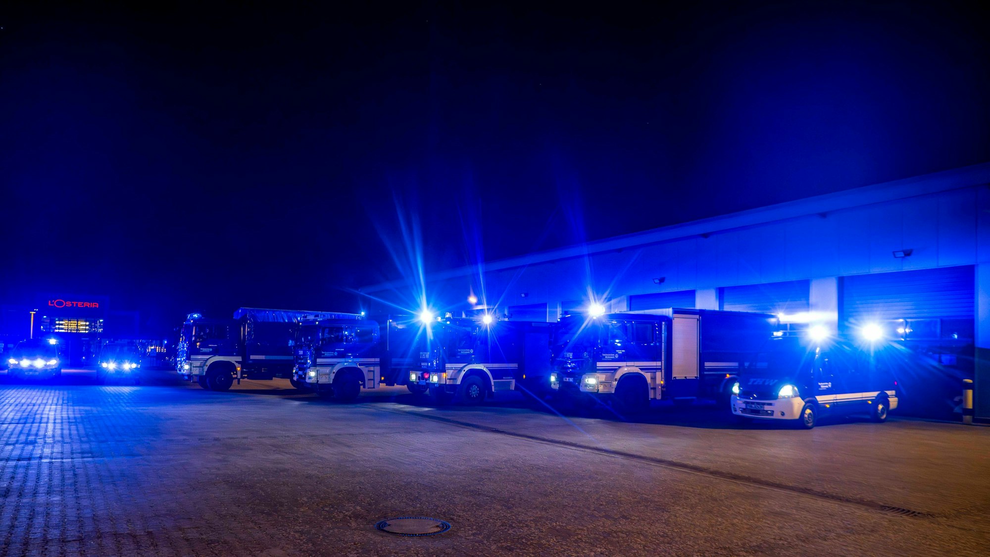 Das Foto zeigt mehrere Fahrzeuge des THW mit eingeschaltetem Blaulicht.