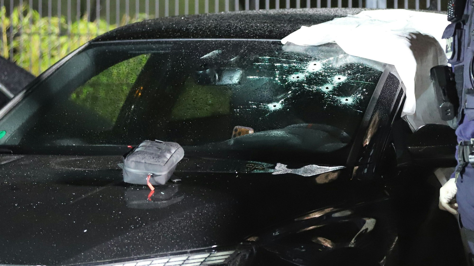 In der Windschutzscheibe eines Pkws sind mehrere Einschusslöcher.