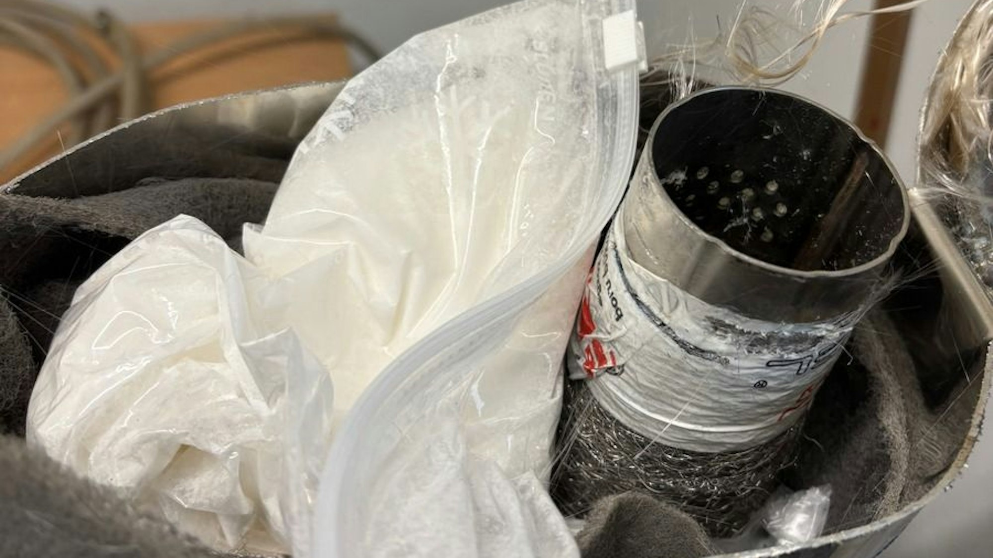 Eine geöffnete Auspuffanlage, in der sich eine Tüte mit Ketamin befindet