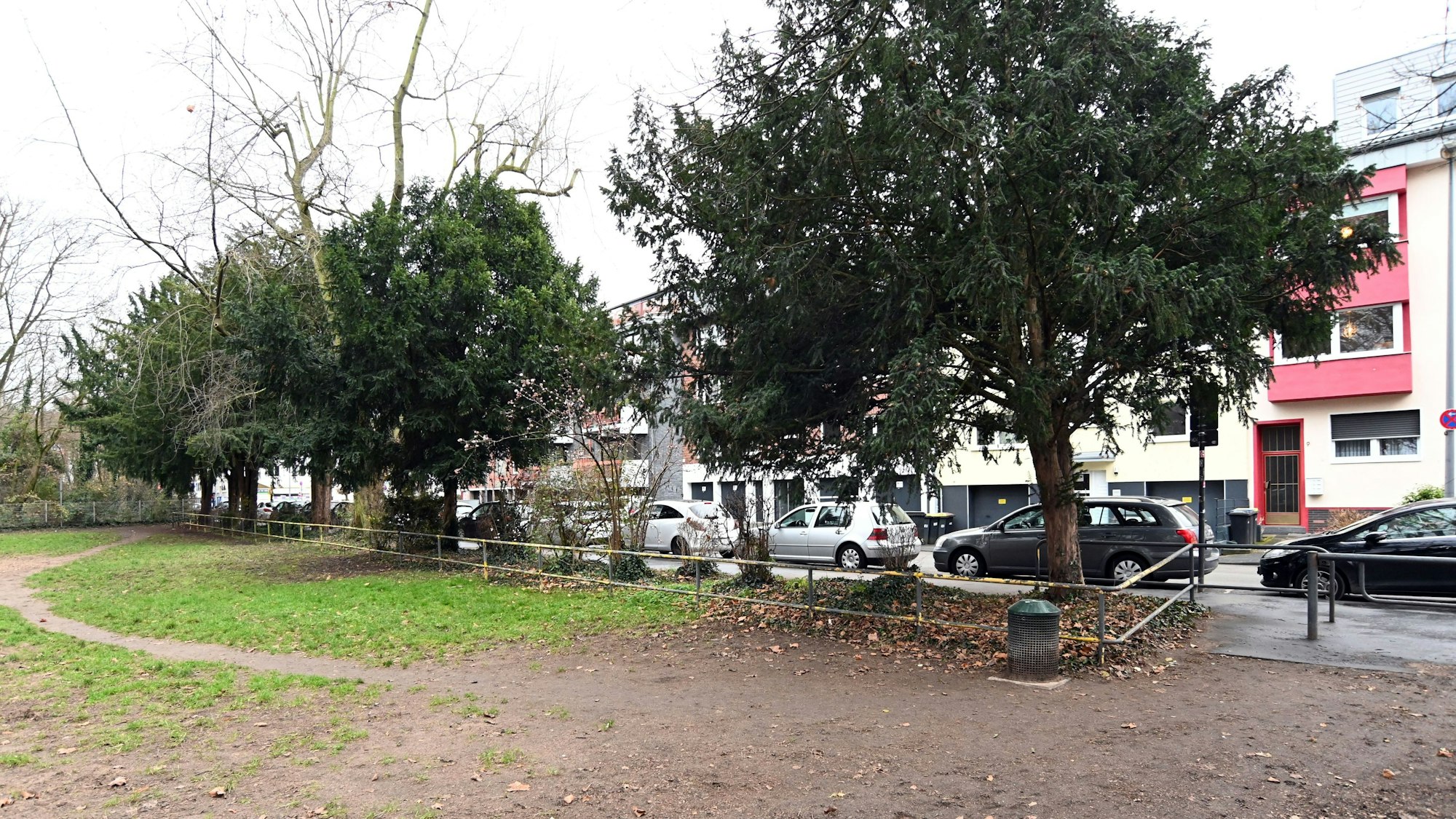 Eine Gasfläche, eingezäunt von der einen Seite. Dahinter eine Straße mit Häusern.