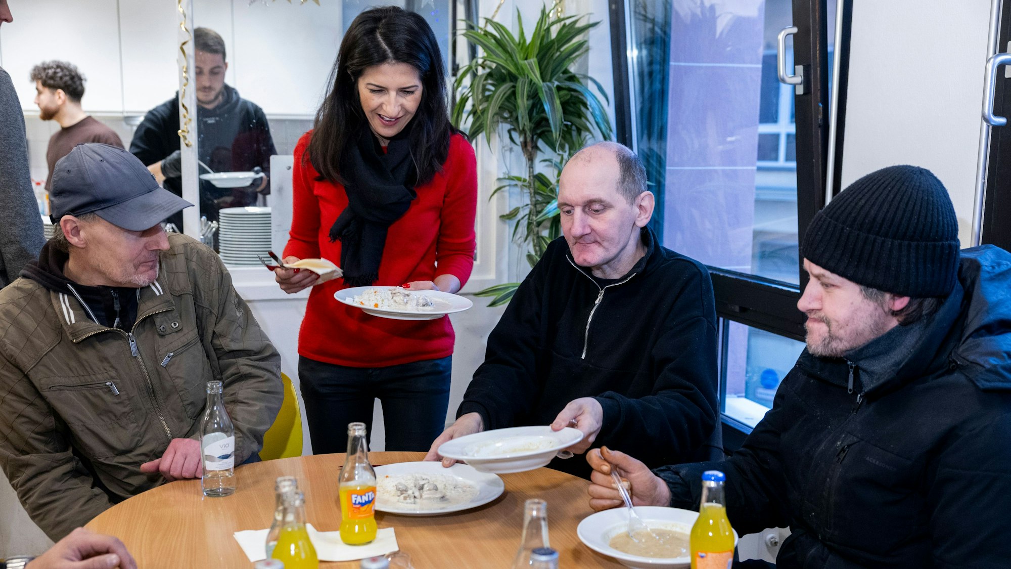 Staatsministerin Serap Güler (roter Pullover) lädt zum Weihnachtsessen für obdachlose und suchtkranke Menschen im SKM.