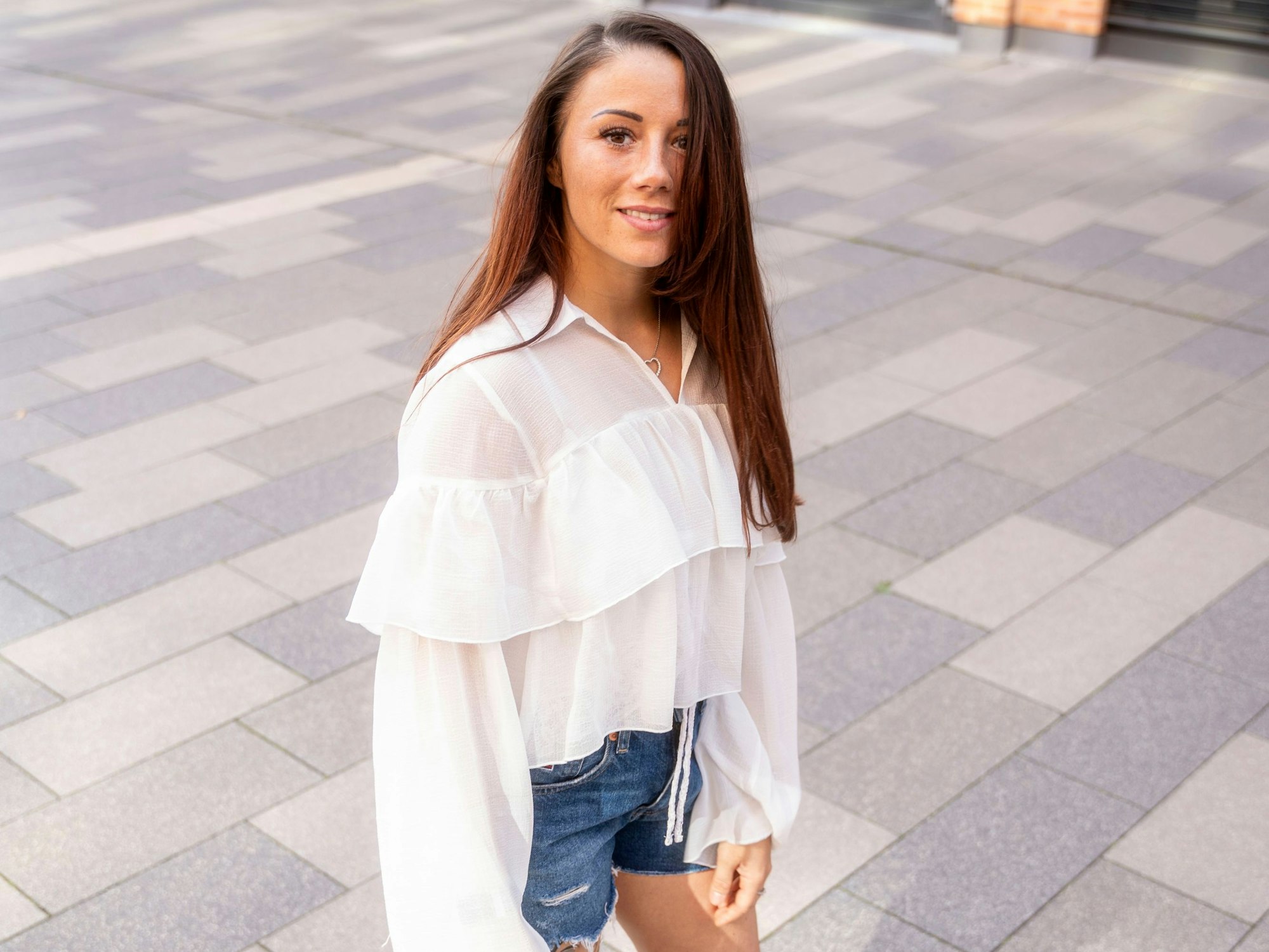 Carrie Schreiner steht in kurzer Hose auf einem Boulevard.