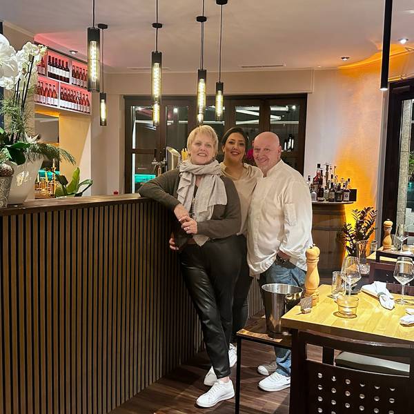 Zwei Frauen und ein Mann stehen an einer Theke in einem Restaurant.