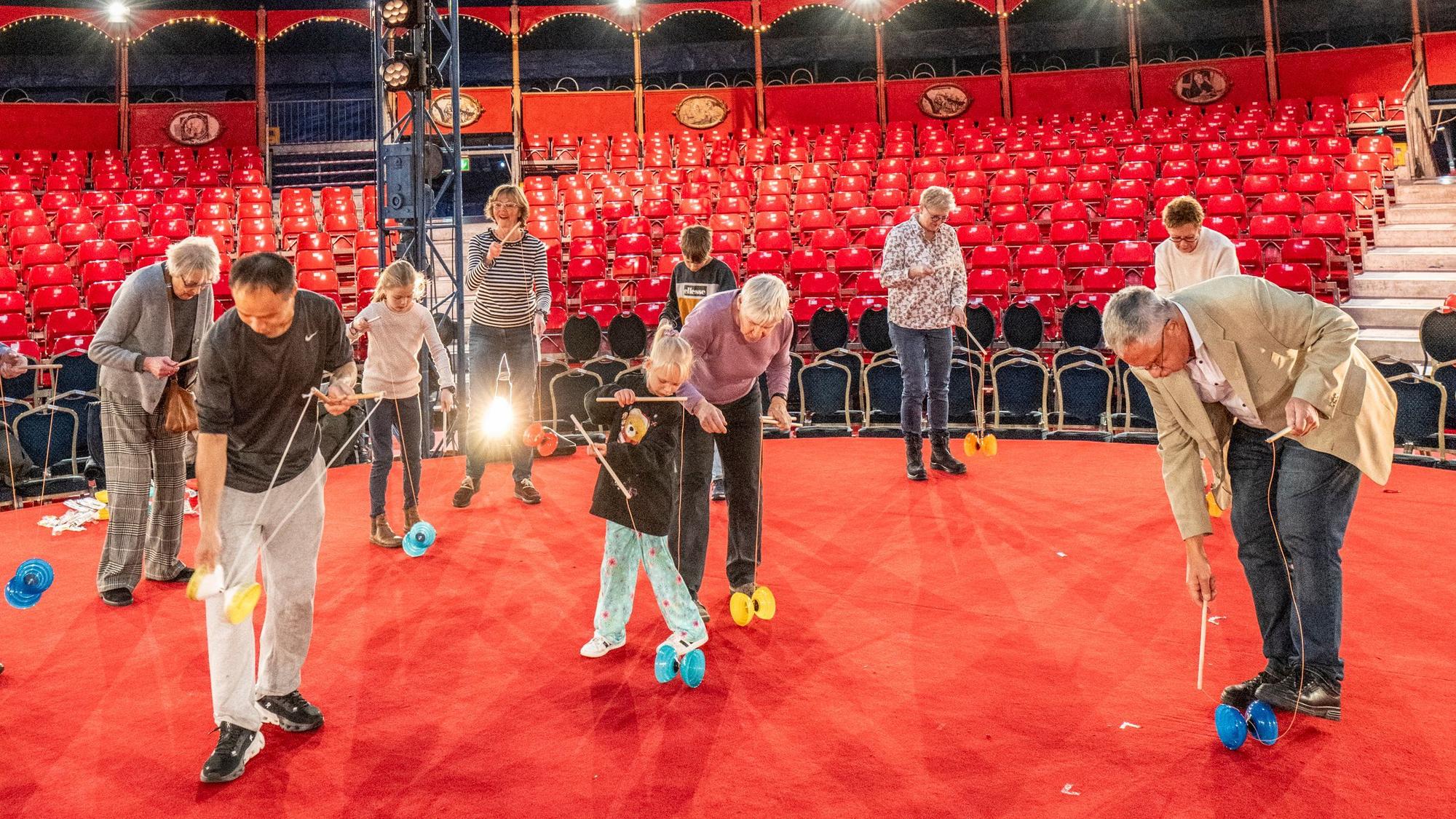 Chu Chuan-Hoein steht mit Leserinnen und Lesern des KStA in der Manege des Kölner Weihnachtscircus, alle haben ein Diabolo und üben.