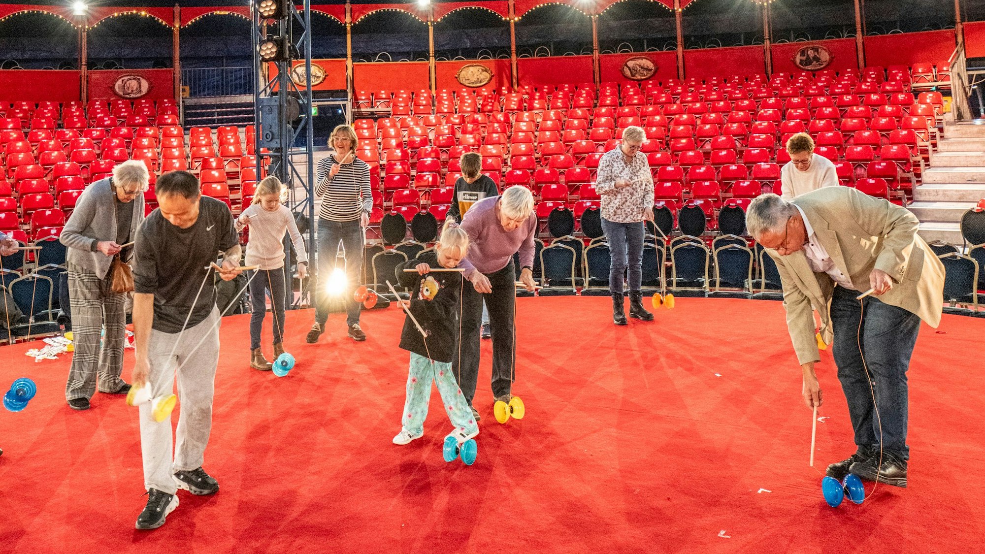 Chu Chuan-Hoein steht mit Leserinnen und Lesern des KStA in der Manege des Kölner Weihnachtscircus, alle haben ein Diabolo und üben.