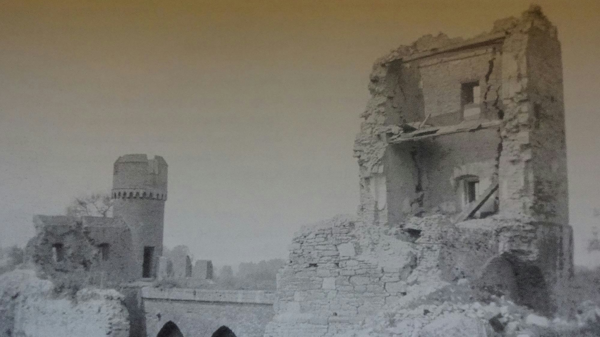 Rechts im Bild befindet sich ein stark beschädigter Teil des Stadttors, links der erhaltene Turm.