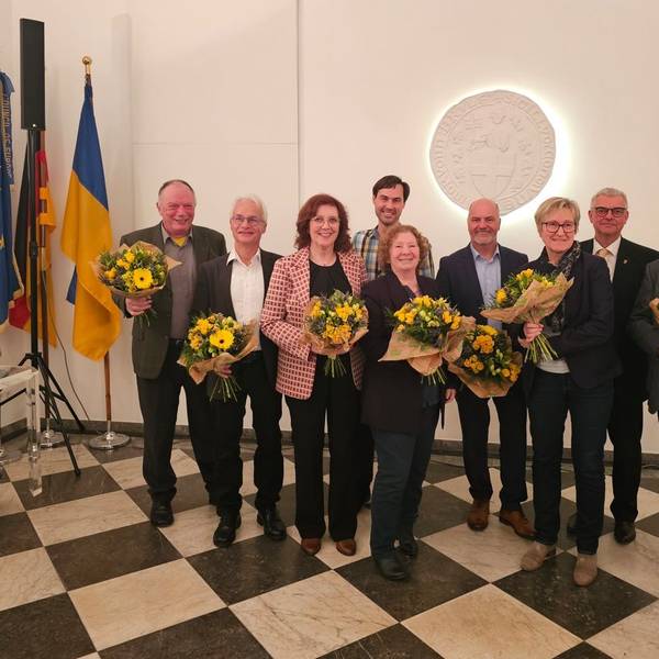 Zu sehen sind Frauen und Männer, die Blumensträuße in ihren Händen halten.