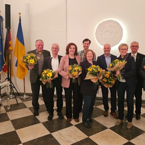 Zu sehen sind Frauen und Männer, die Blumensträuße in ihren Händen halten.