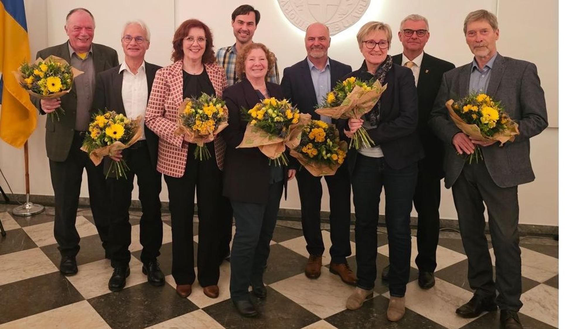 Zu sehen sind Frauen und Männer, die Blumensträuße in ihren Händen halten.
