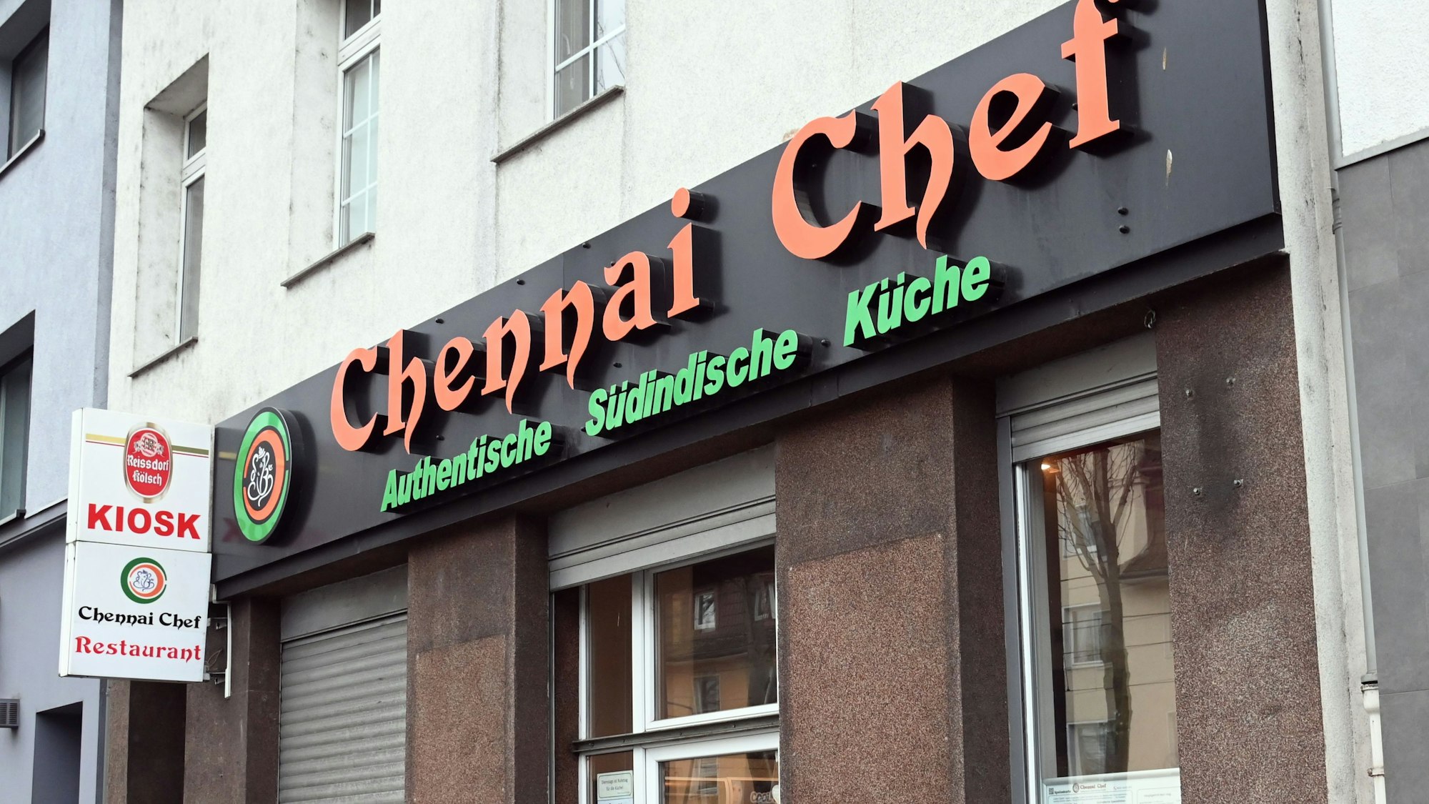 Fassade mit halb heruntergelassenen Rolläden ist zu sehen.