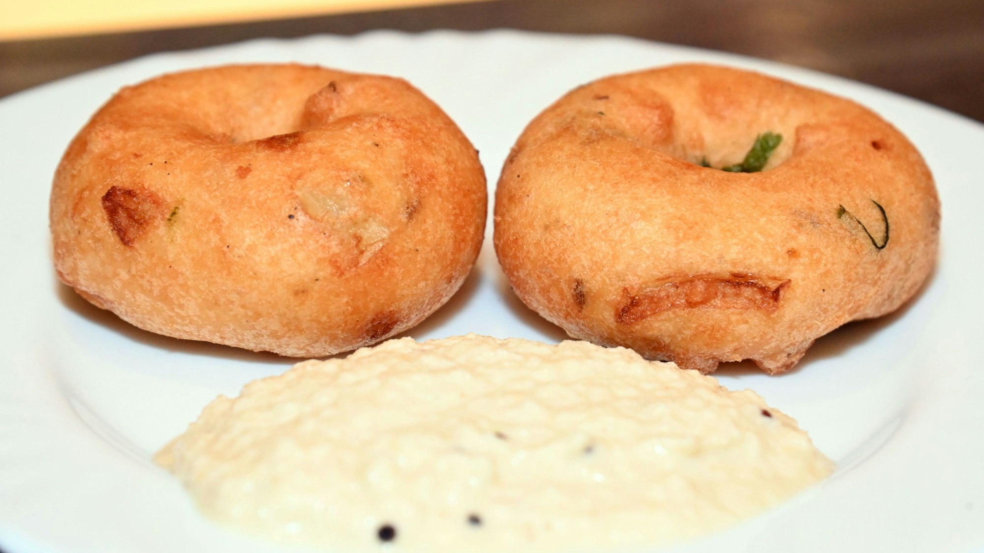 Zwei Donut ähnliche Teigkringel auf einem weißen Teller