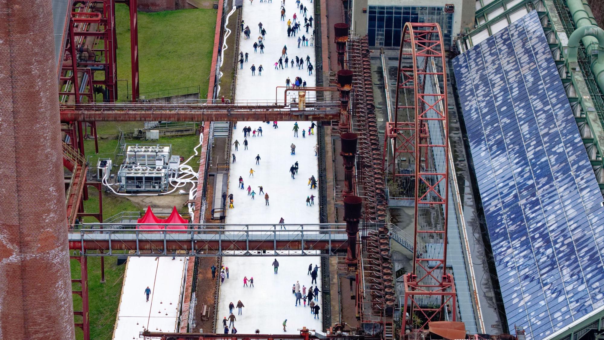 Menschen tummeln sich auf der Eisbahn in der Zeche Zollverein. Die 150 Meter lange Bahn ist noch bis zum 6. Januar geöffnet.