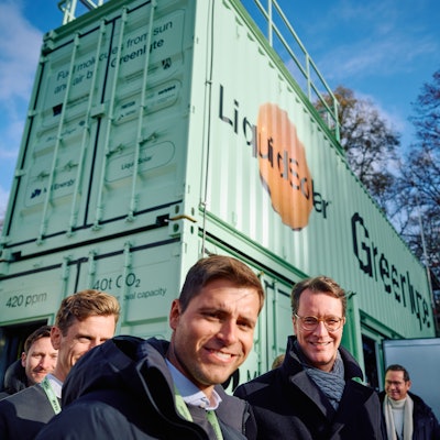 Der NRW-Ministerpräsident steht mit Vertretern von Greenlyte vor einen grünen Container.