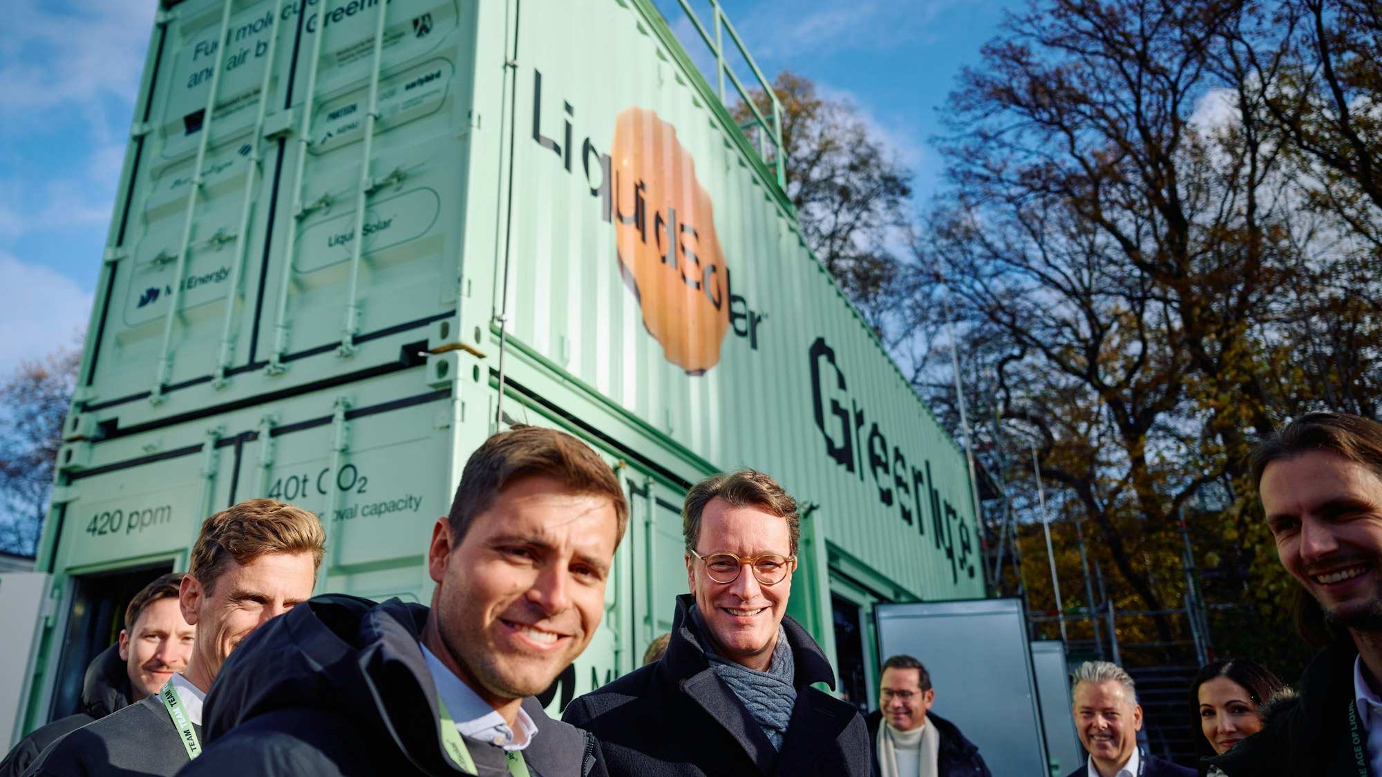Der NRW-Ministerpräsident steht mit Vertretern von Greenlyte vor einen grünen Container.