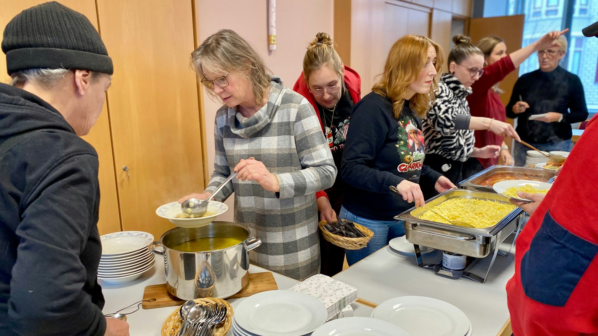 Hinter dem Buffet stehen die Mitarbeiterinnen und schöpfen das Essen in die Teller der Gäste.