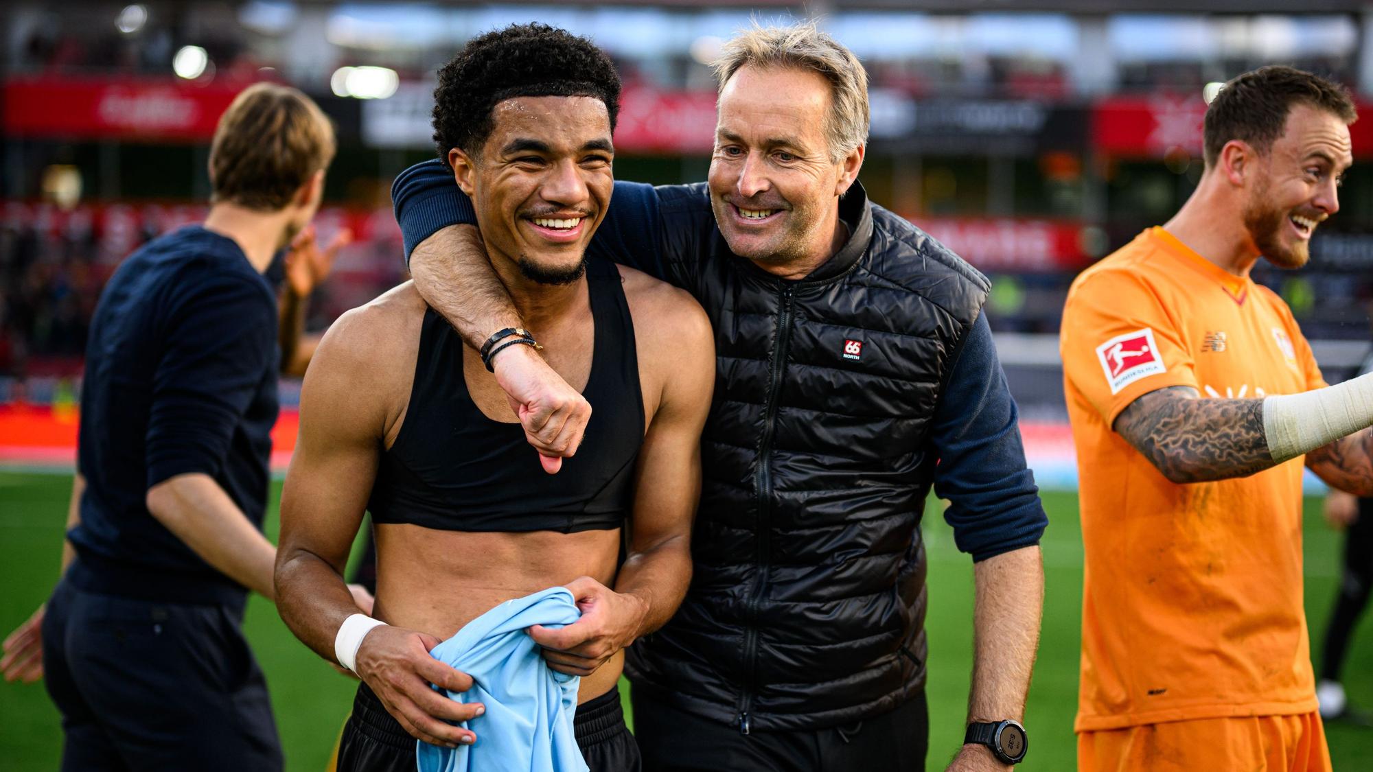 Leverkusens Trainer Kasper Hjulmand mit seinem Spieler Malik Tillman. Links: Simon Rolfes, rechts Mark Flekken.