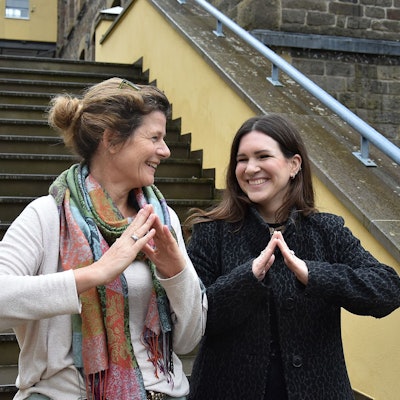 Zwei Frauen bilden mit ihren Händen ein symbolisches Dach.
