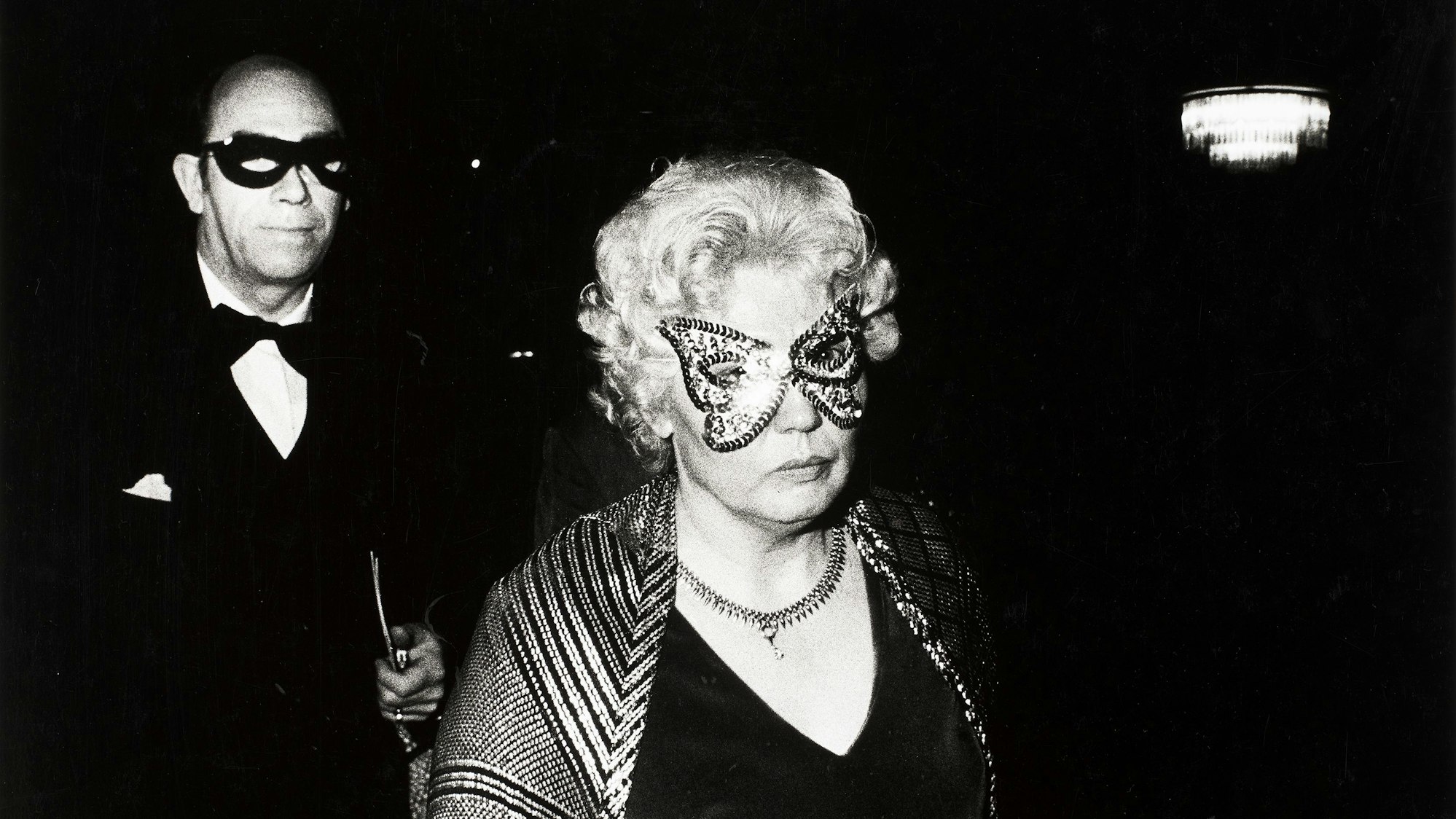 Ein maskiertes Paar schaut skeptisch in die Kamera des Fotografen.