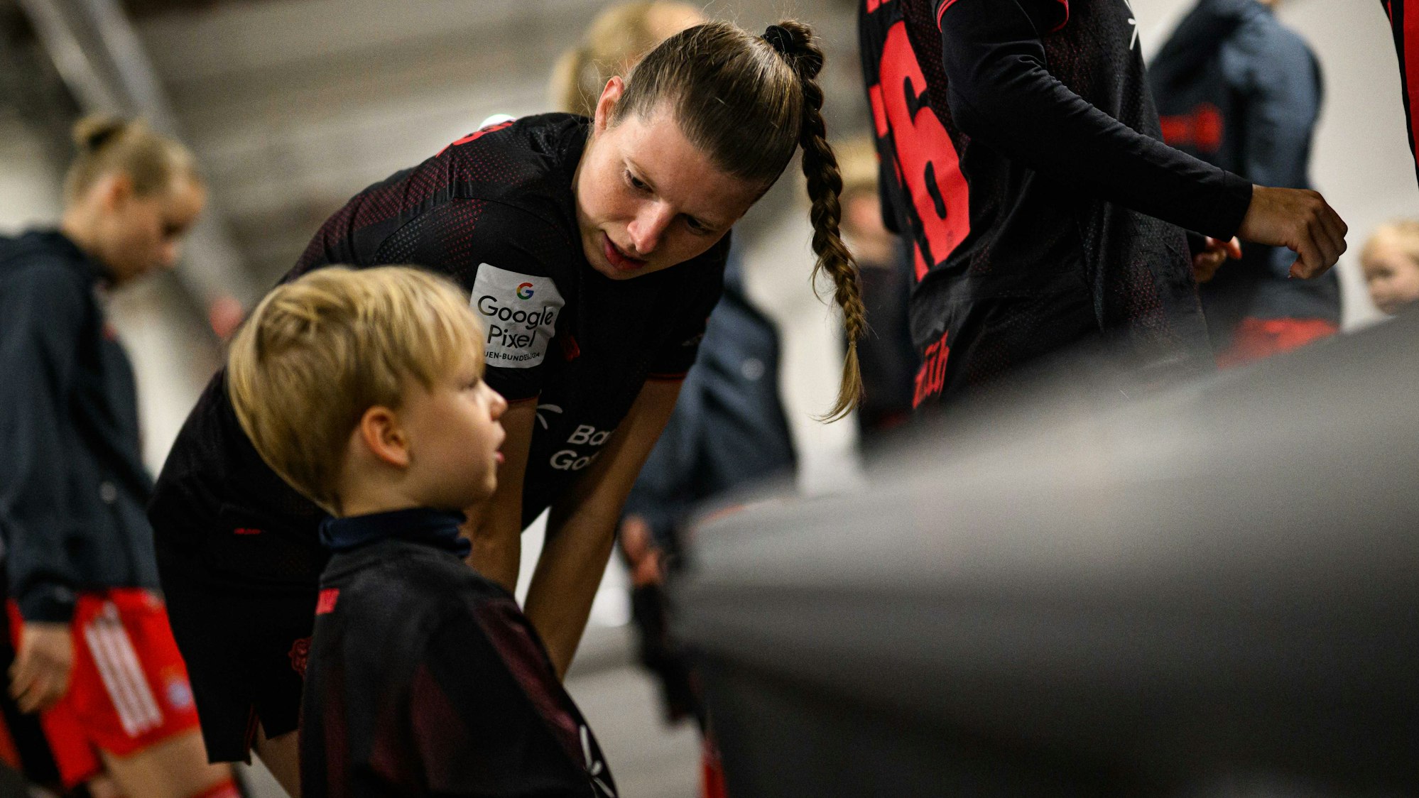 Eine Leverkusener Fußballerin spricht beruhigend mit dem Einlaufkind.