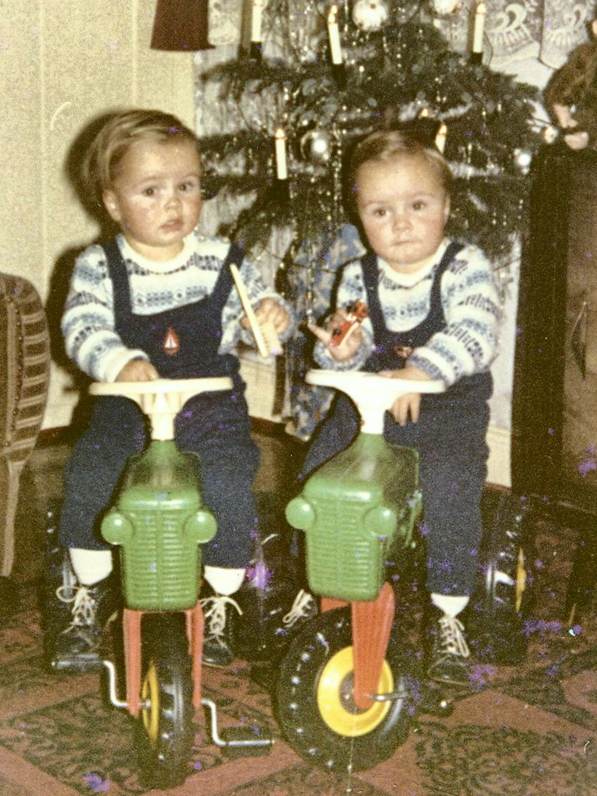 Zwei Jungs auf Tretrollern vor einem Weihnachtsbaum.