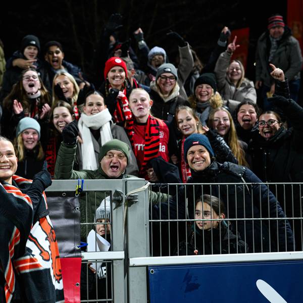 Julia Mickenhagen steht, in eine Decke gehüllt, vor dem Zaun hinter dem ihre Fans sind.
