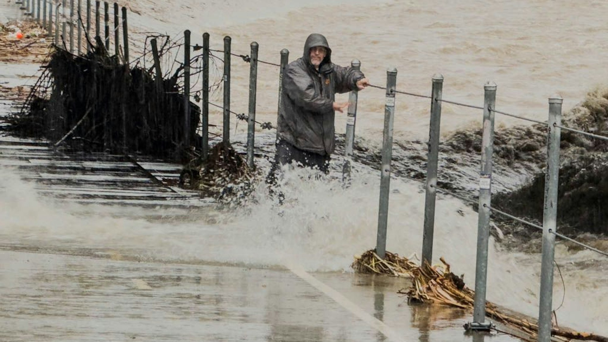 Ein Mann hält sich an einem Geländer fest, nachdem er während eines Sturms an Heiligabend in Glendales in einen reißenden Kanalisationsschacht getreten ist.