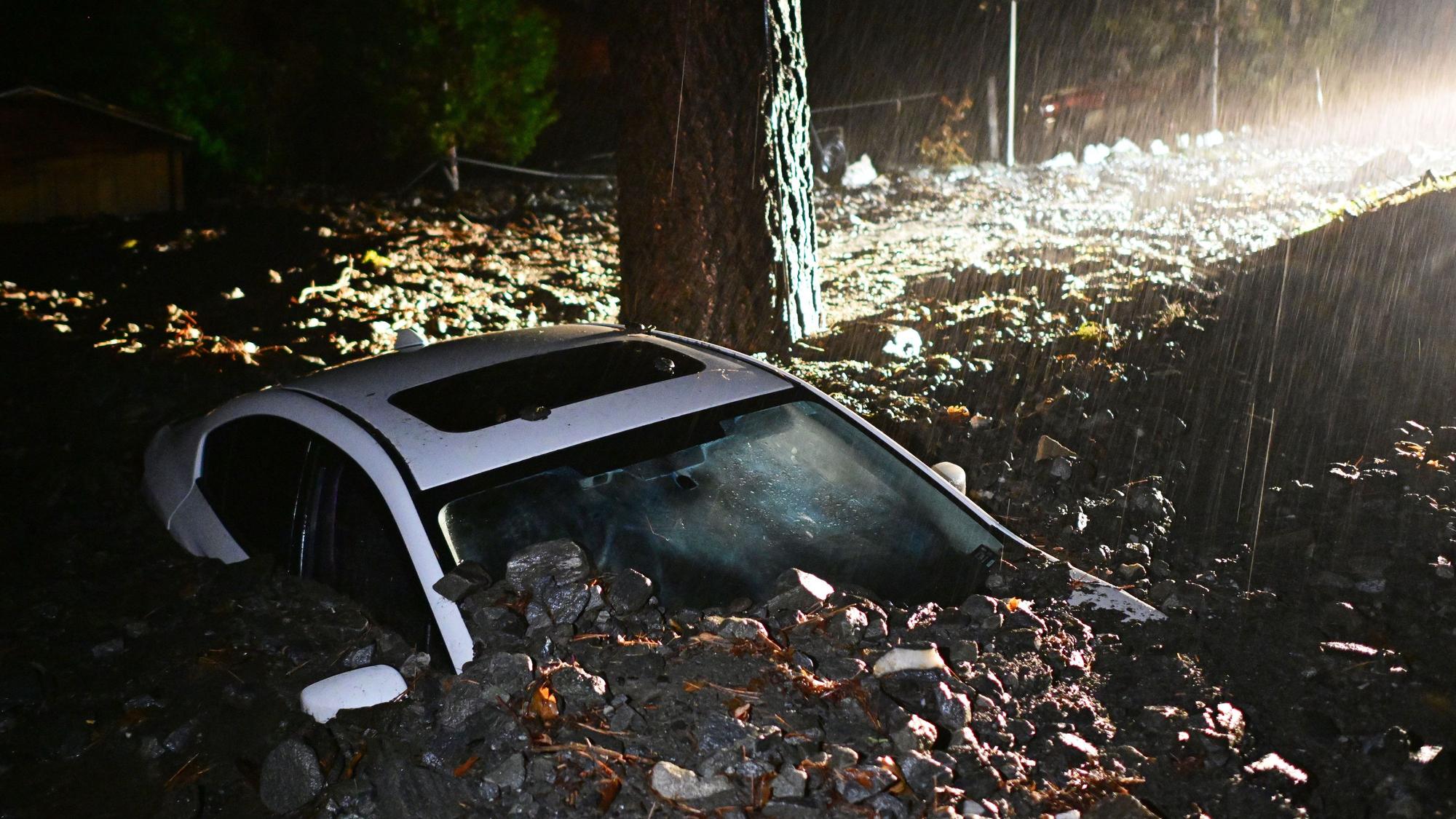 Ein Auto liegt nach einer Überschwemmun in Wrightwood, Kalifornien, im Schlamm begraben.