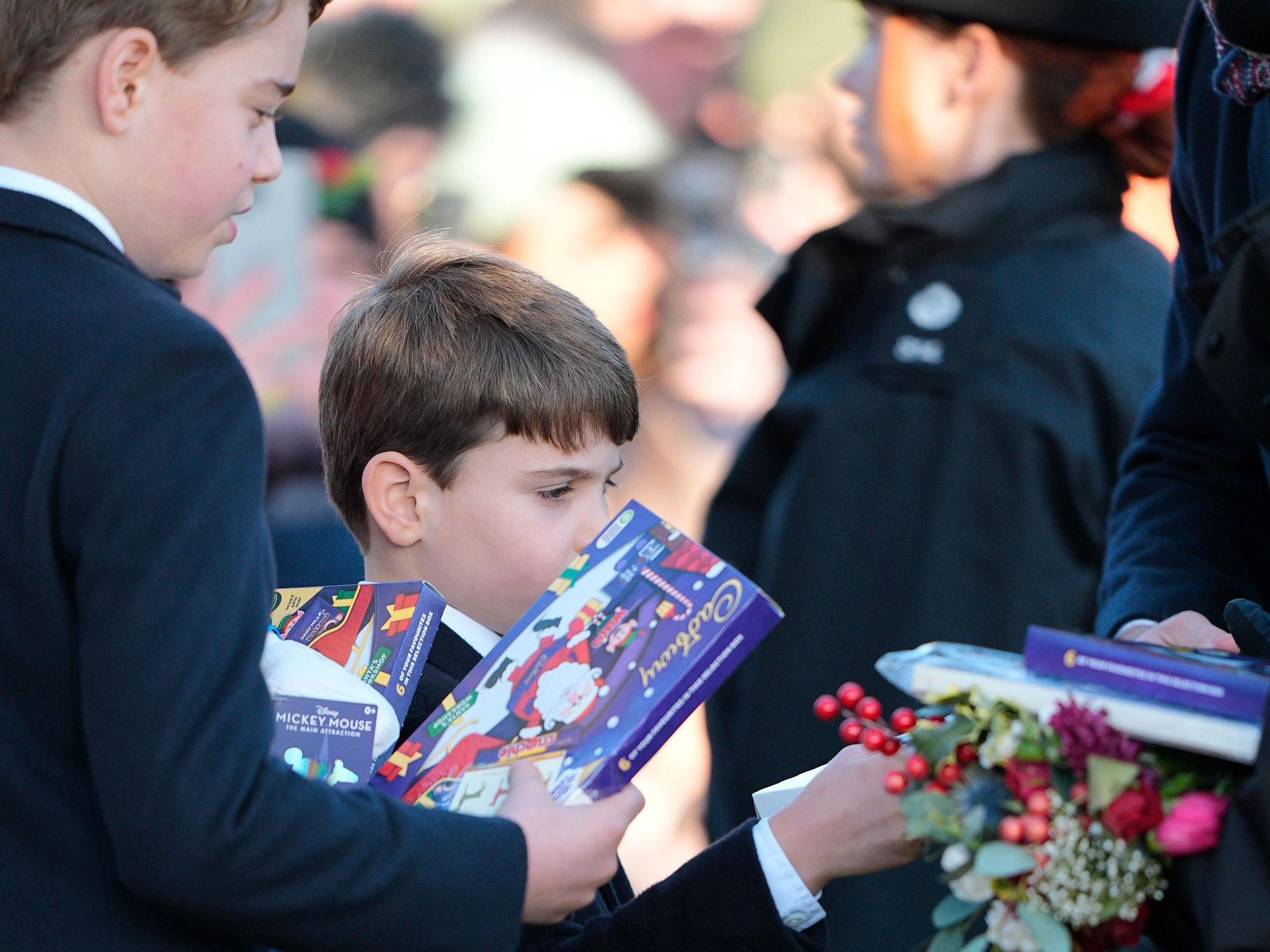 Prinz George und Prinz Louis halten Geschenke in den Händen, die ihnen von Mitgliedern der Öffentlichkeit vor dem Weihnachtsgottesdienst am Morgen in der St. Mary Magdalene Church in Sandringham, Norfolk, überreicht wurden.