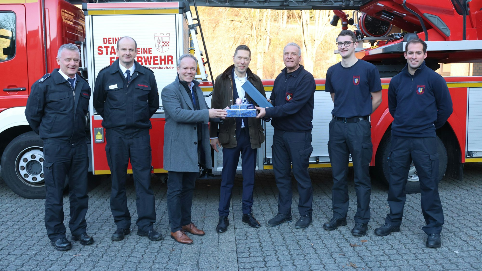 Eine Gruppe von Männern vor einem Feuerwehrauto.