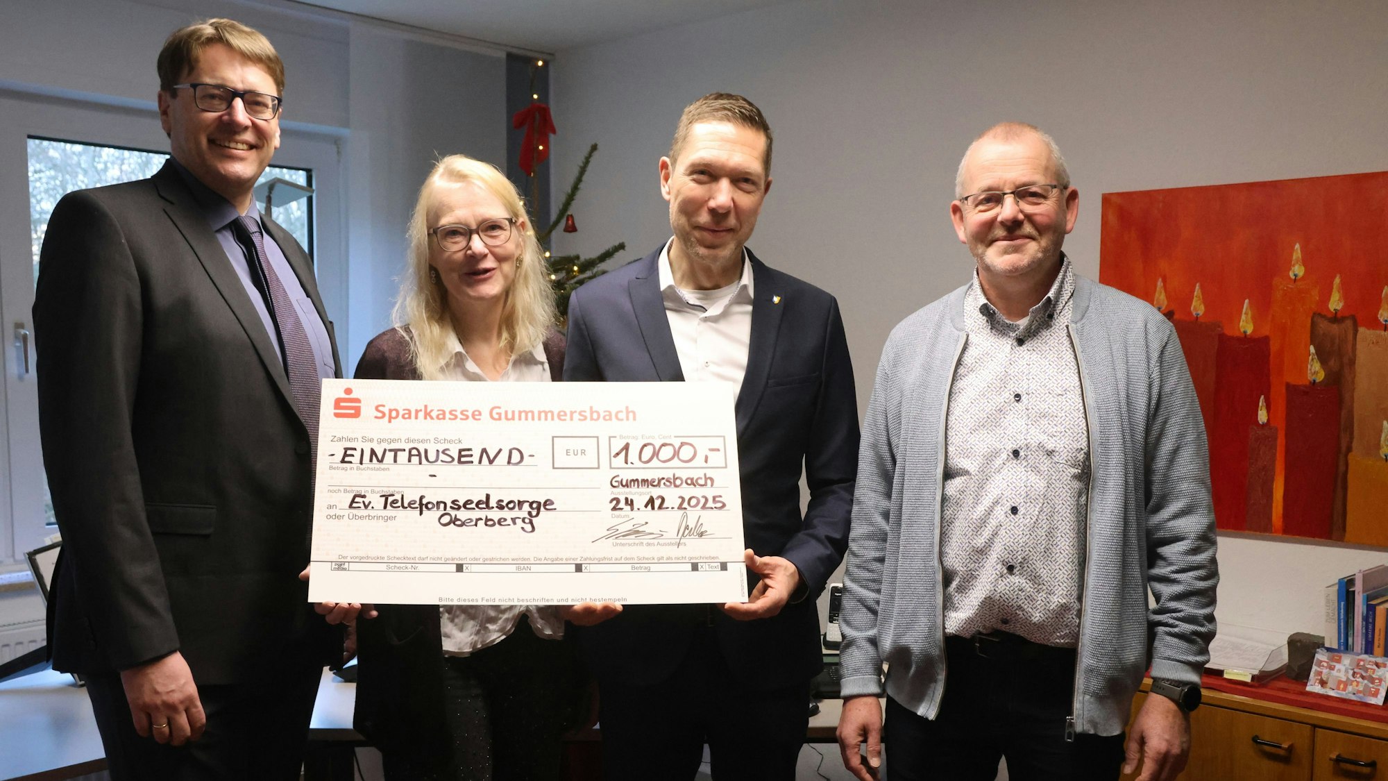 In den Räumen der Telefonseelsorge stehen die vier Personen mit einem Spendenscheck.